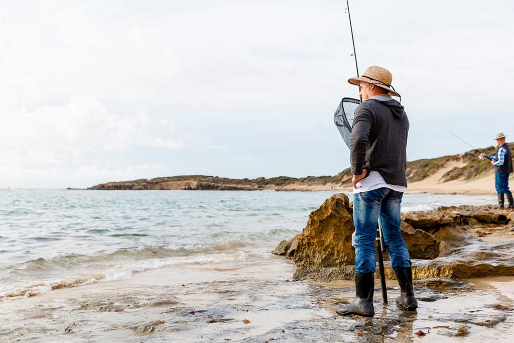 Küstenlinie Dänemark - Angler an der felsigen Küste Dänemarks, eingetaucht in das Hobby, das Meer und die Natur.