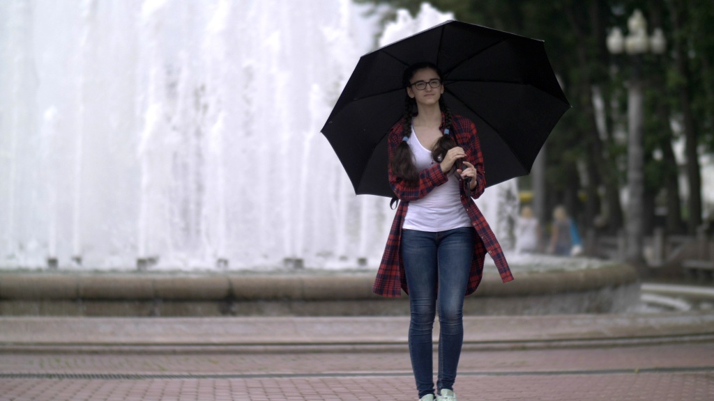 7-Tage Wetter Dänemark – Junge Frau mit Schirm vor einem Springbrunnen.