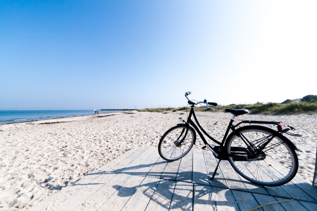 Ferienhausanbieter Dänemark - Sanfte Sanddünen mit natürlichem Strandhafer unter einem weiten blauen Himmel, einladend für einen erholsamen Urlaub.