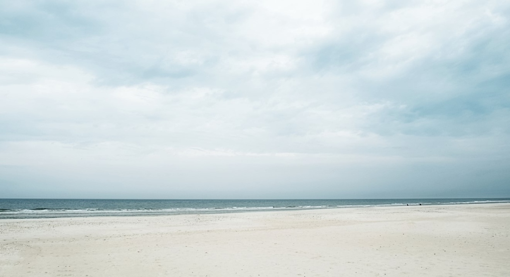 Der Houstrup Strand zeigt sich als ruhiger Strandabschnitt mit feinem Sand und einem weiten Blick auf das Meer unter einem großzügigen Himmel.