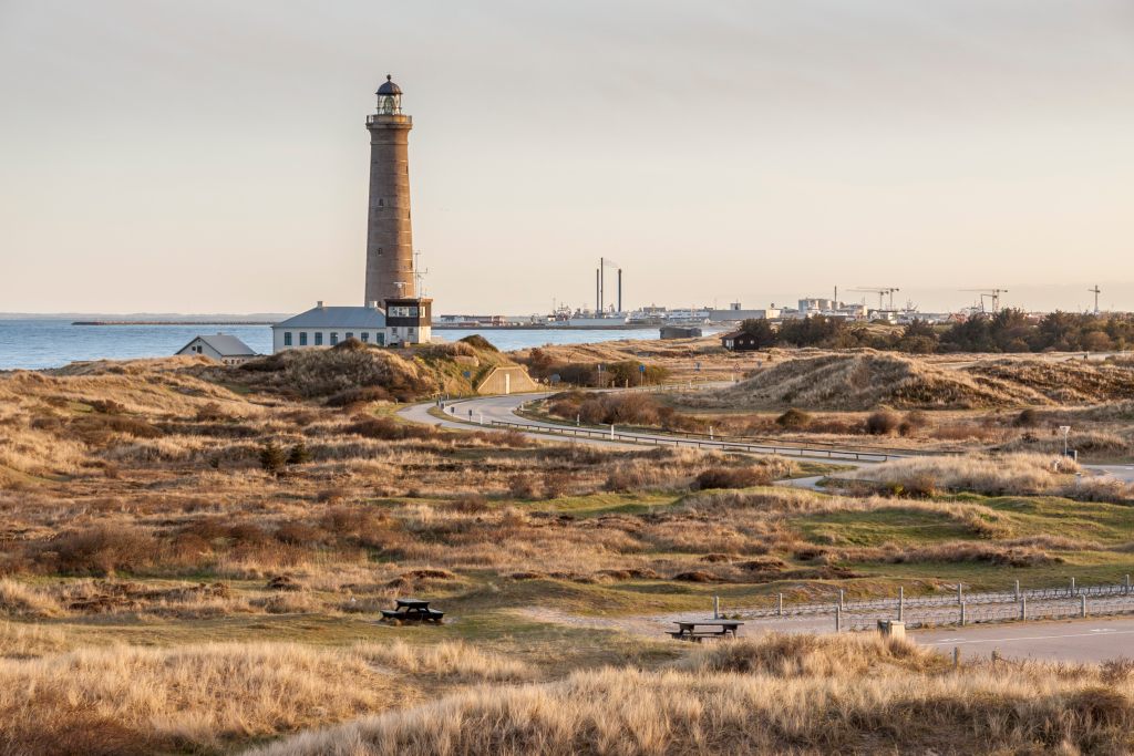 Skagen - Der hohe, schlanke Leuchtturm von Skagen steht wachsam an der Spitze Dänemarks, umgeben von weiten Dünengebieten und mit Blick auf das ruhige Meer bei Sonnenuntergang.