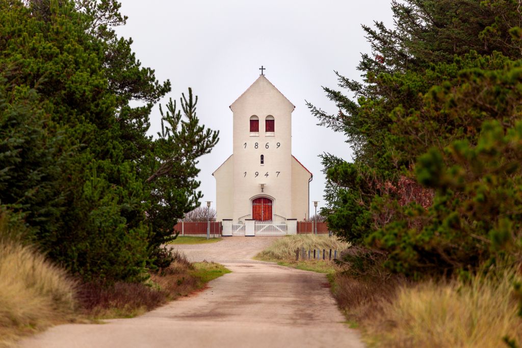 Årgab Dänemark Sehenswürdigkeiten - Eine weiße Kirche aus dem Jahr 1869, erneuert 1947, steht majestätisch am Ende einer von Kiefern gesäumten Straße, ein stilles Zeugnis der Geschichte in der malerischen Landschaft Årgabs.