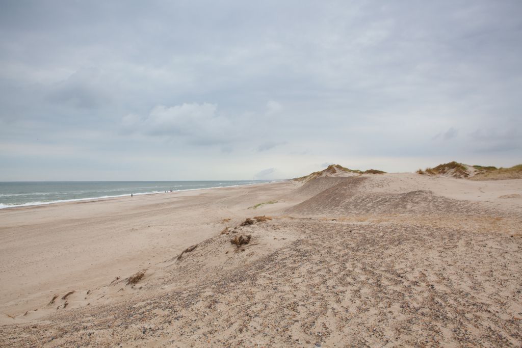Årgab Strand Dänemark - Weite Aussicht auf den ruhigen Årgab Strand in Dänemark mit seinen charakteristischen Sanddünen und dem sanften Wellenschlag des Meeres an einem bewölkten Tag.