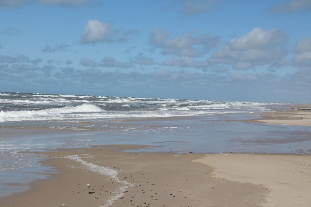 Blokhus Ferienhäuser - Der raue Charme der Nordsee mit aufgewühlten Wellen und schaumigen Gischt am Strand von Blokhus, umrahmt von einem Himmel voller wechselnder Wolken.
