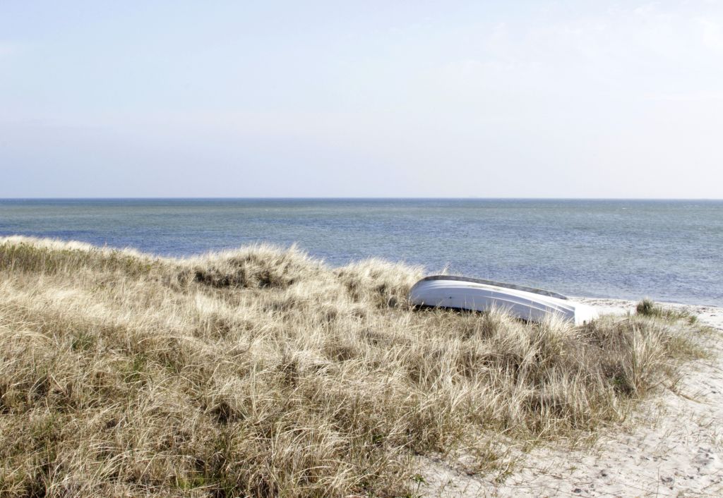 Ebeltoft Strände mit einem umgekippten Boot im Dünengras.