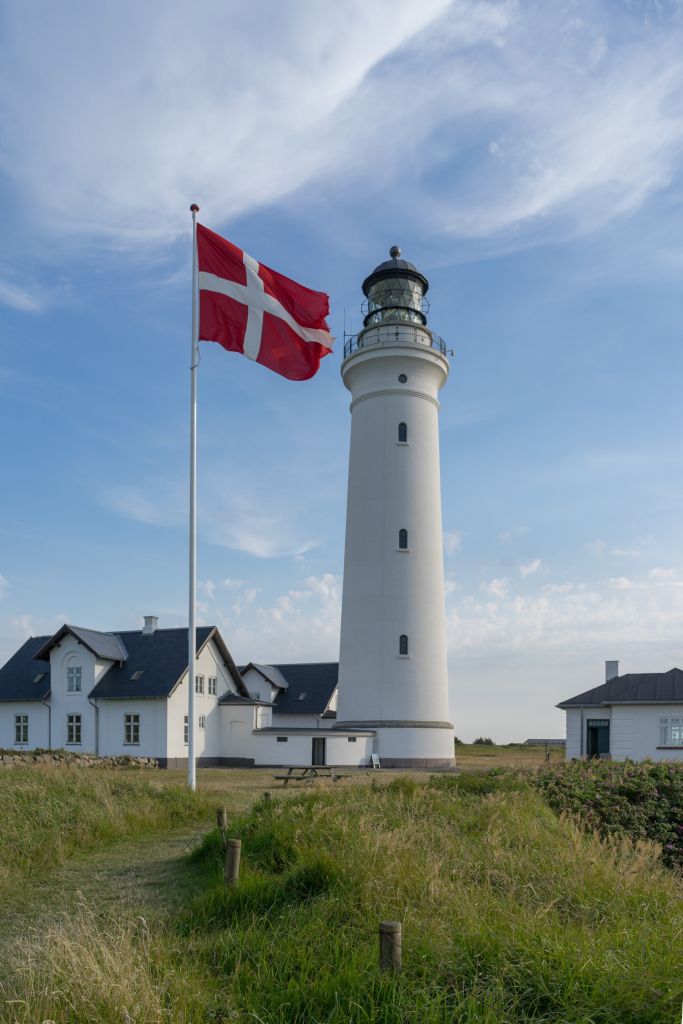 Ferienhäuser Hirtshals neben einem Leuchtturm mit der dänischen Flagge.