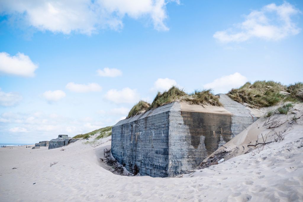 Ferienhaus Westjütland - Alte Bunker aus dem Zweiten Weltkrieg eingebettet in die Dünenlandschaft an einem Strand in Westjütland, Zeugen der Geschichte und heutige Wahrzeichen der Region.