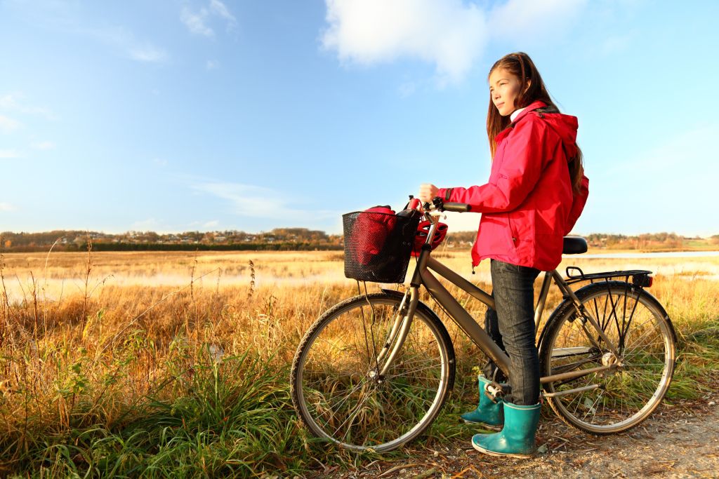 Klegod Dänemark - Ein junges Mädchen hält ein Fahrrad auf einem Feldweg in Klegod, Dänemark, mit der malerischen, goldenen Landschaft im Hintergrund.