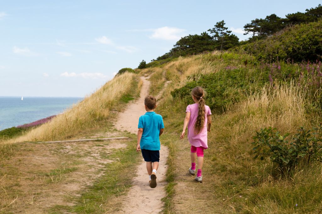 Klegod einkaufen - Zwei Kinder wandern auf einem Pfad in der Natur, eine Szene, die die friedliche Atmosphäre nahe den Einkaufsmöglichkeiten in Klegod einfängt.