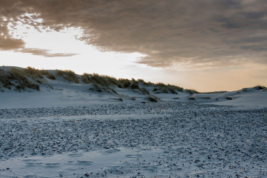 Nordstrand Skagen – Die dramatische Schönheit des dänischen Winters wird durch die kontrastreiche Landschaft mit dem von Schnee bedeckten Strand und den robusten Dünen unter einem bewölkten Himmel hervorgehoben.