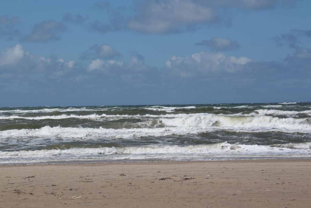 Wetter Blokhus - Schaumige Wellen rollen an den Strand von Blokhus, begleitet von einem Himmel voller flüchtiger Wolken, was das dynamische Wetter an Dänemarks Küste widerspiegelt.