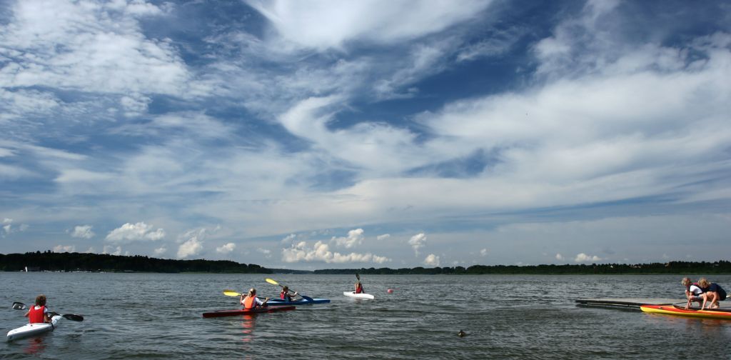 Wetter Klegod - Menschen genießen das Paddeln auf dem ruhigen Wasser in Klegod, Dänemark, unter einem weitläufigen blauen Himmel mit malerischen Wolken.