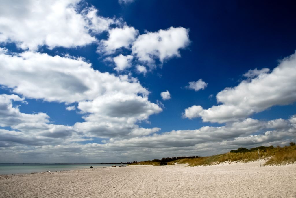 Wetter Skagen – Dramatischer Himmel mit flauschigen Wolken über dem weißen Sandstrand in Skagen, der die wilde Schönheit Dänemarks widerspiegelt.